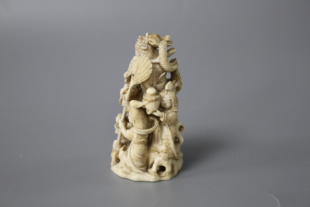 A Japanese Meiji period carved ivory group of a goddess and dragon with attendants, signed to the underside, height 8cm